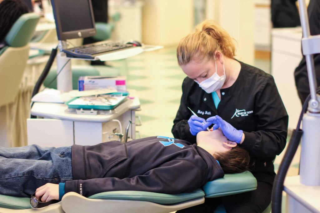 Mary Cay Koen Orthodontics assistant examining the bite of a teen patient