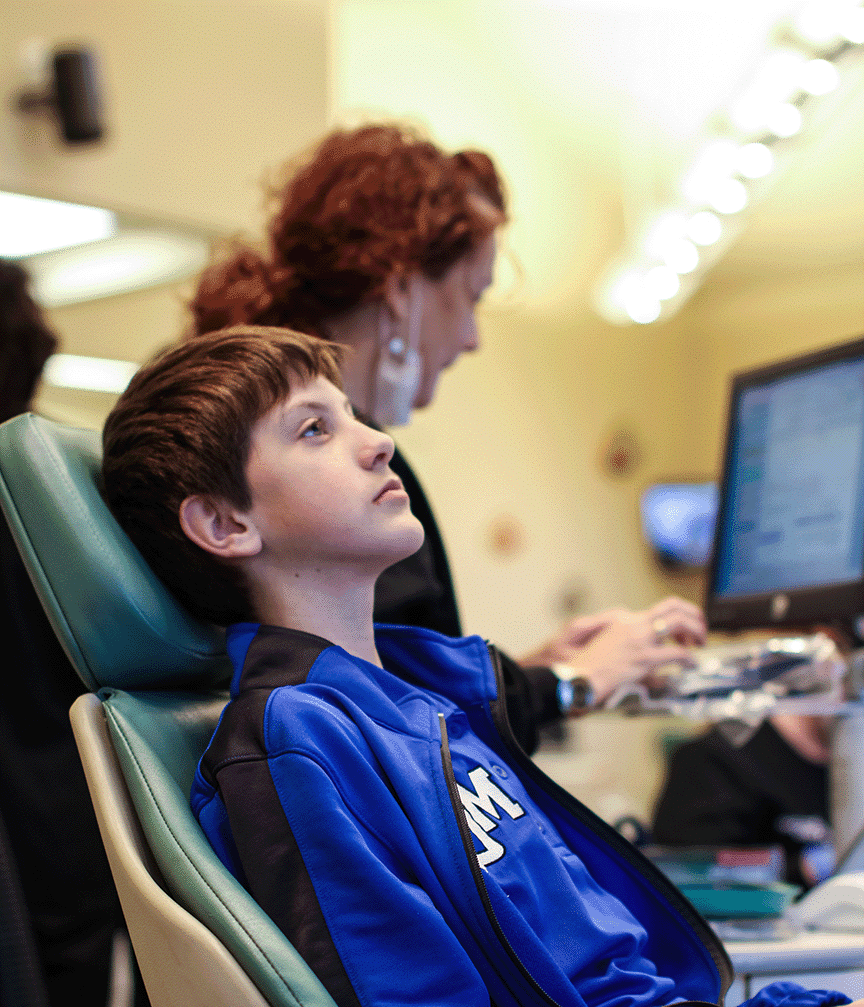 Teen in a patient chair at Mary Cay Koen Orthodontics as an employee reviews his exam results