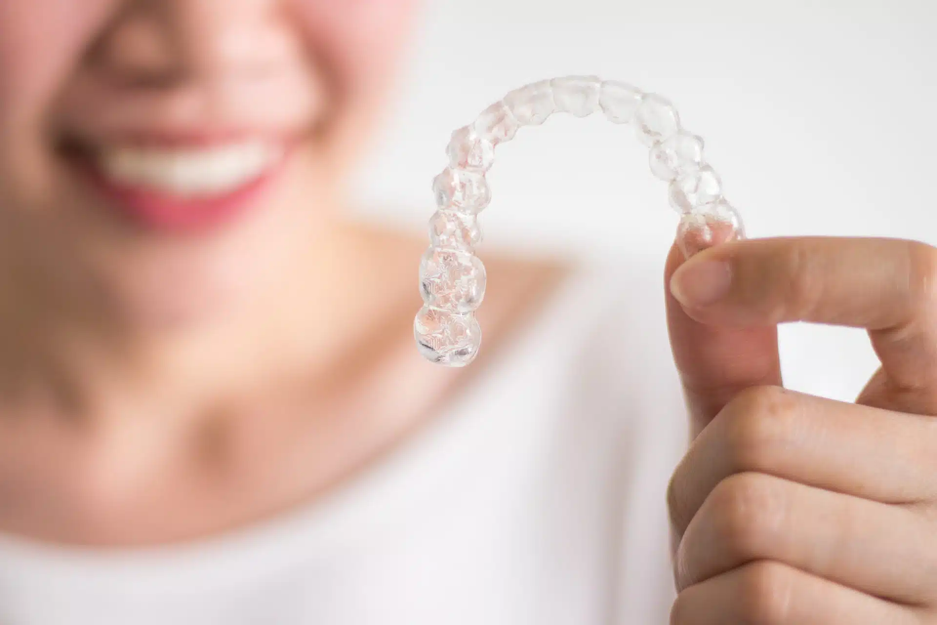 a woman holding invisalign aligners up in front of her
