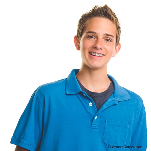 a teenage boy with braces and a blue shirt standing in front of a white background
