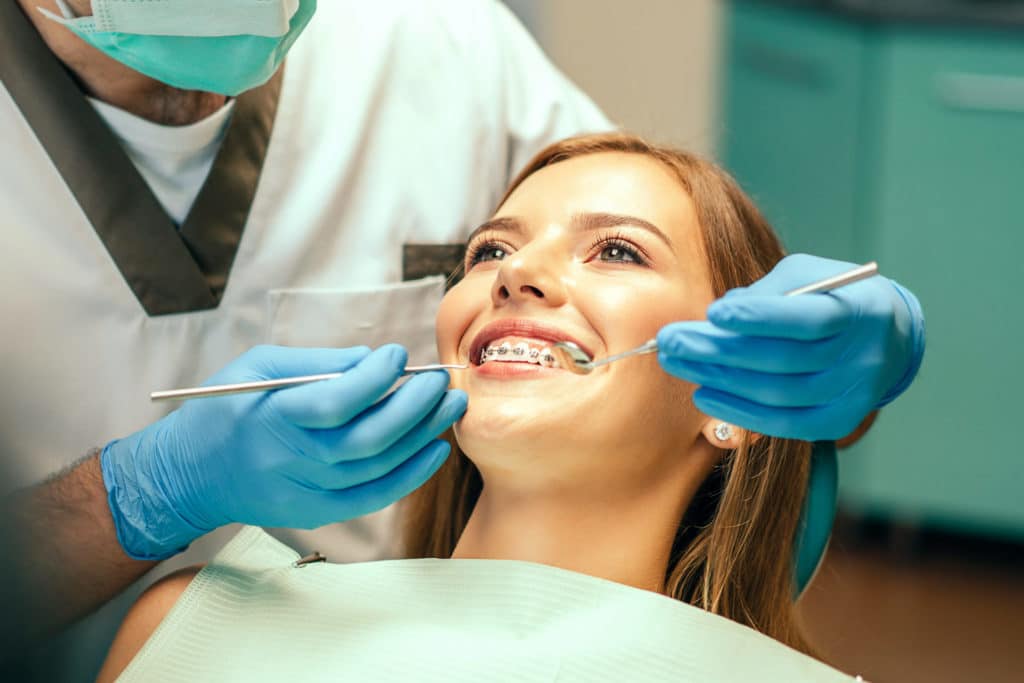 a female orthodontic patient getting her braces inspected by her orthodontist