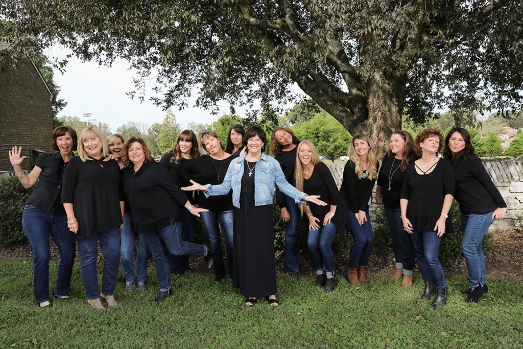 A group of women posing in front of a tree.