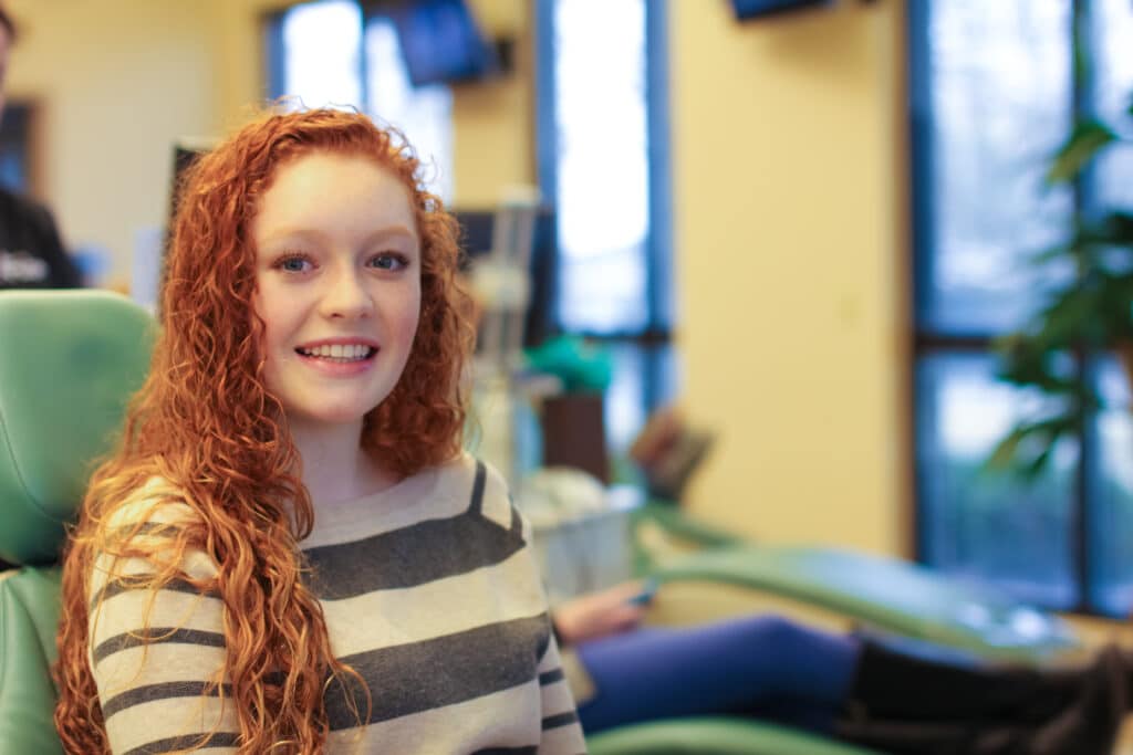 Teenager with vibrant red hair smiling in the office of her orthodontist near White House, TN