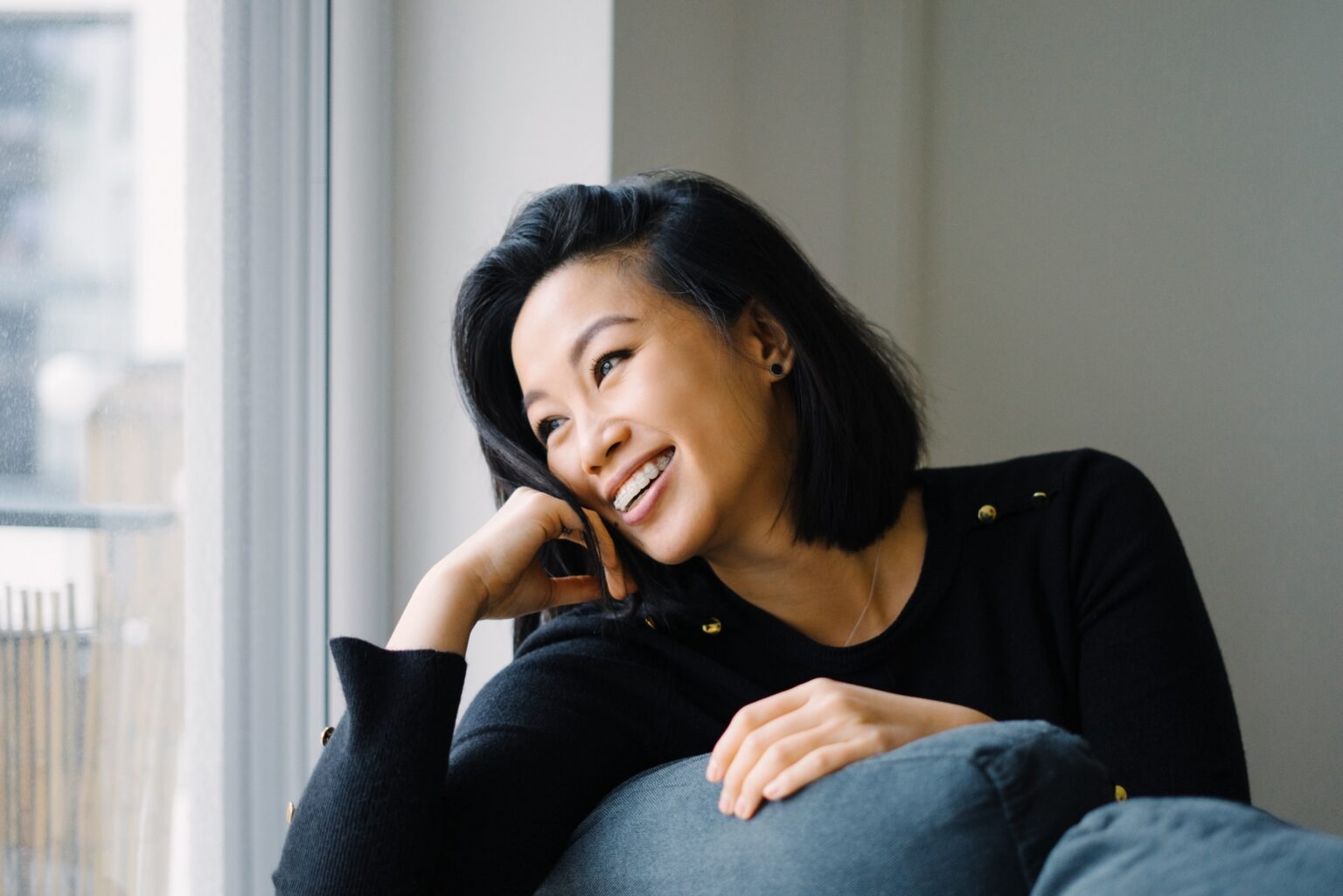 Woman with braces for adults in Nashville smiling while looking out of a window