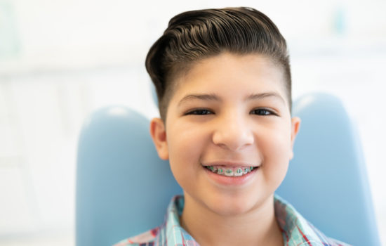 Closeup portrait of smiling cute Latin boy wearing braces in a dental clinic